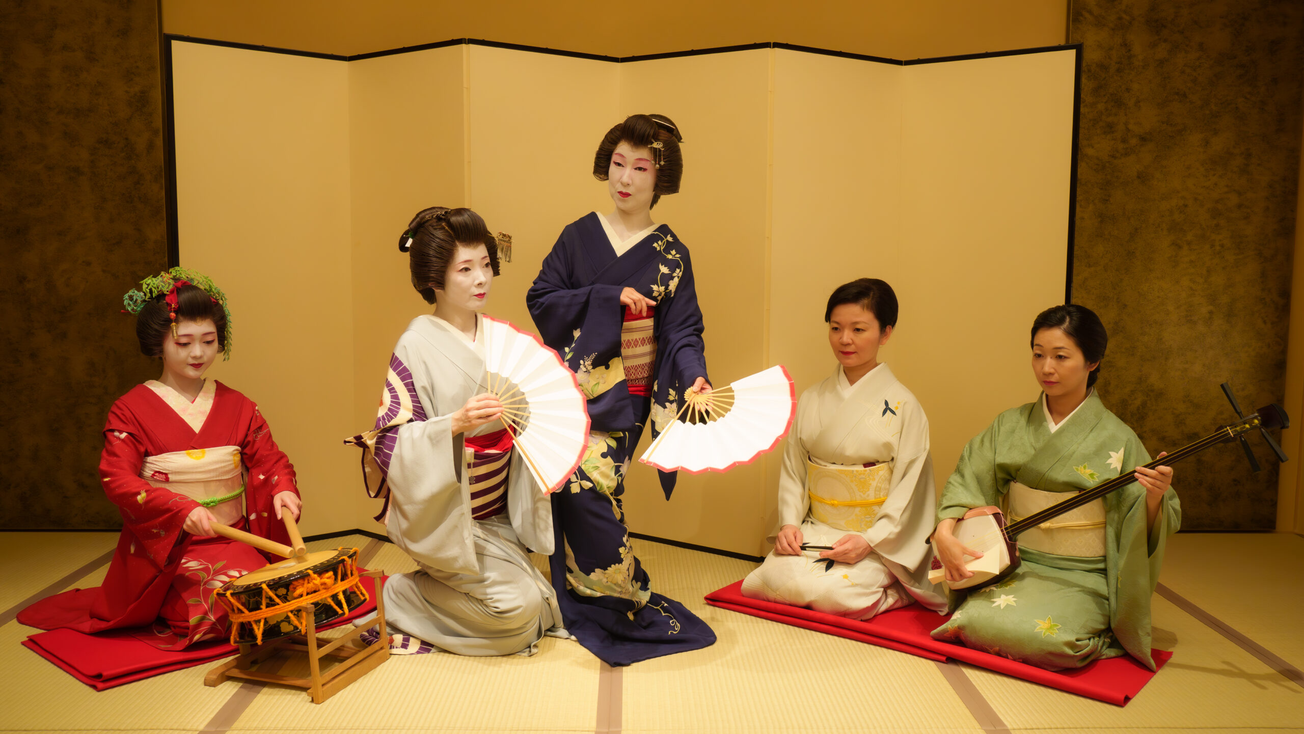 Jikata geisha playing shamisen beside tachikata geisha dancing in the tatami room