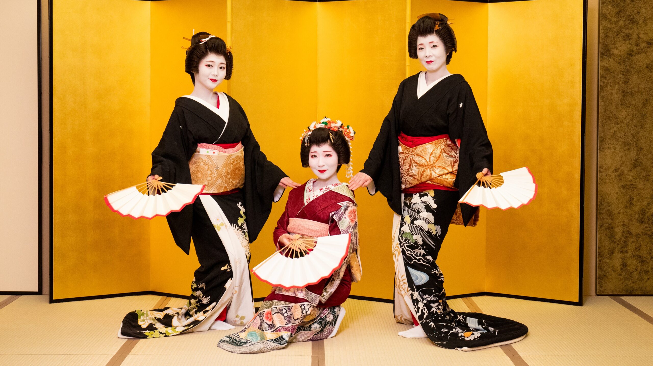 Three Asakusa geisha performing a fan dance before a gold screen at Miyakodori