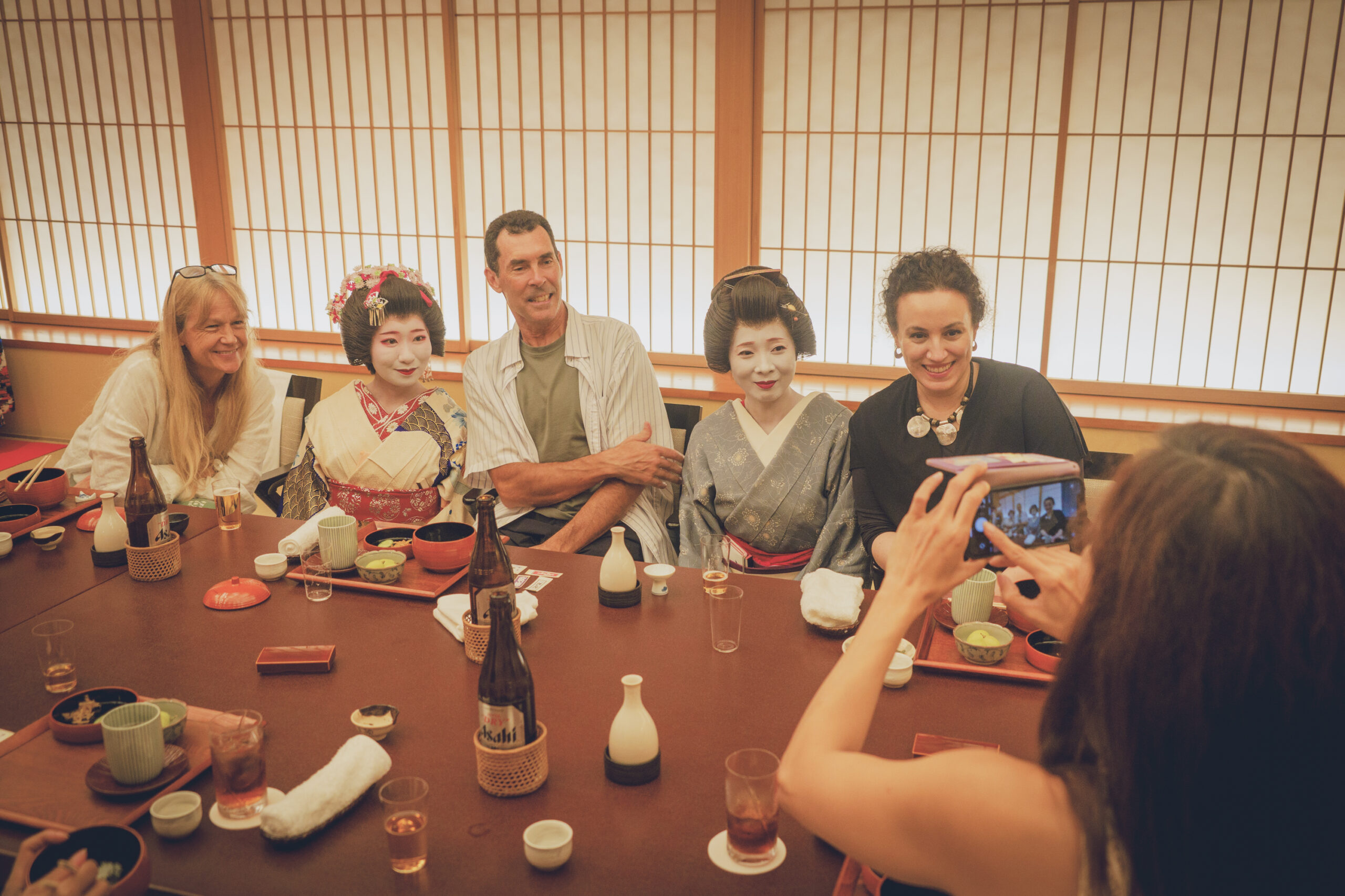 Two or three geisha with guests enjoying music and play in a private tatami room